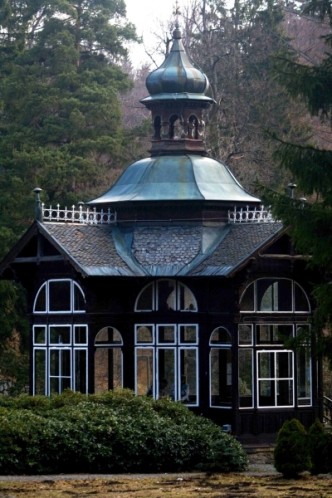 Na obrázku lázeňský pitný pavilón v Lázních Karlova studánka.Dřevěná stavba zapadá do zdejší krásné horské přírody