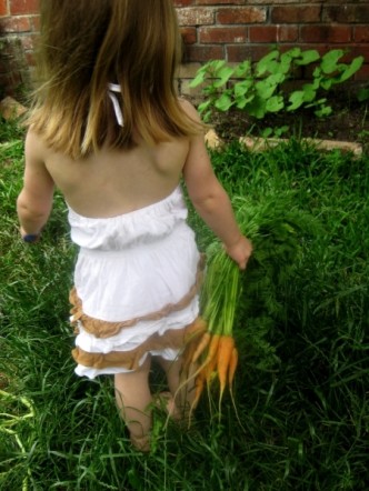 holčička s mrkví na zahrádce, fotka k článku s receptem na mrkvovou polévku
