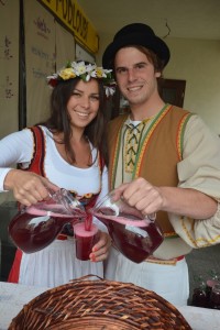 Mladý pár v historických kostýmech rozlévá červený burčák na Znojemském vinobraní